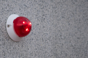 Wall mounted red emergency light signal hanging on an office building on the street