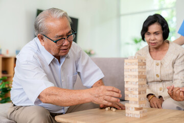 Dementia therapy in playful way. Group of senior elder people stay at nursing home, enjoy activity.relation playing Jenga or tumbling tower wood block game. Training fingers and fine skills