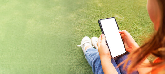 phone with copy space in the hands of a child close-up on a background of green grass banner, wireless technology, online learning and shopping, communication in social networks, children's blogger,