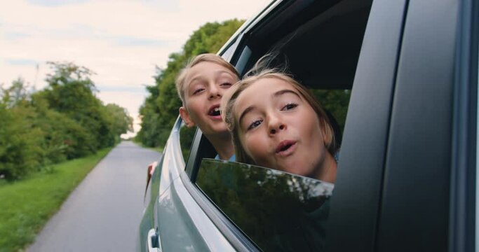 Carefree little children leaned out of the car window and smiled. Happy family enjoy and having fun together with outdoor lifestyle activity on road trip vacation.