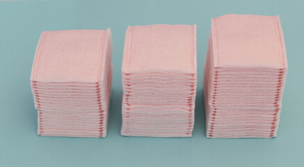 Almoadillas de algodon en color rosa sobre fondo azul, usadas para el cuidado facial. 