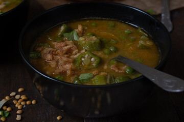 Vegan lentil, okra and peas soup, topped with crispy onions, served in black bowls