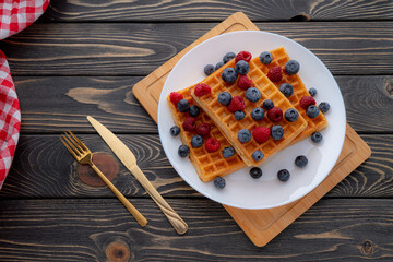 Waffle with berries, strawberries and honey on wooden table top view