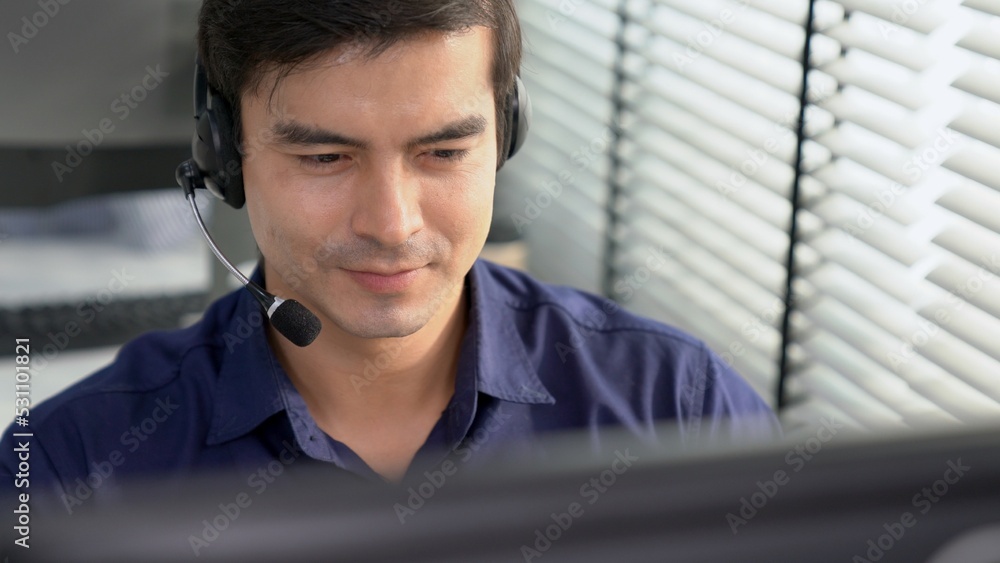Aufkleber young competent asian male call center agent working at his computer while simultaneously speaking w