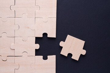 Business concept with wooden jigsaw puzzle on black background.