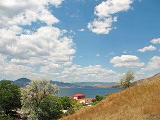 Fototapeta premium village by the sea, against the background of mountains and blue sky with clouds