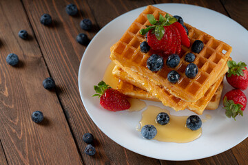 Waffle with berries, strawberries and honey on wooden table top view