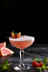 Drinks and cocktails. A light red drink with grapefruit, raspberries, mint and ice in a glass on a black table. Bar menu. Background image, copy space