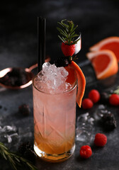 Drinks and cocktails. Beverage light red and white with grapefruit, rosemary and ice in a glass on a black table. Bar menu. Background image, copy space