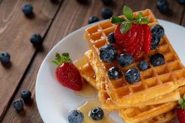 Waffle with berries, strawberries and honey on wooden table top view