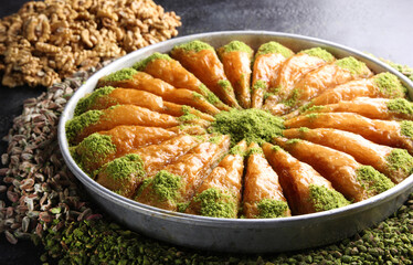 Oriental sweets. Pahlava with nuts, pistachio in a large dish on a black table. Turkish dessert. Background image, copy space, horizontal, top view, flatlay