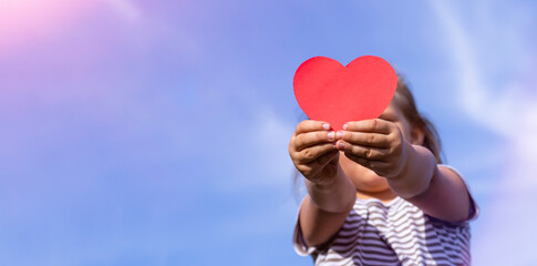 A child with a paper heart in his hands. Congratulations on Valentine's Day. Child on the...