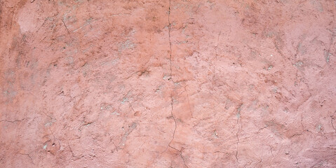 The texture of old painted concrete. The concrete background is dusty pink. The background of a painted wall with cracks. Banner of an old painted plastered wall.