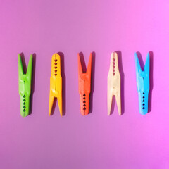 five plastic colorful clothespin in row on bright purple background.minimal creative composition.