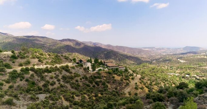 Aerial drone footage of Holy monastery of Panagia Amirous in Apsiou, Limassol, Cyprus. Establish scene of the religious stone church, ceramic roof tiles and surrounding mountain landscape from above