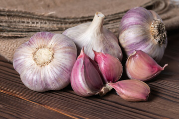 Garlic cloves on wooden table and sackcloth. Fresh peeled garlics and bulbs.