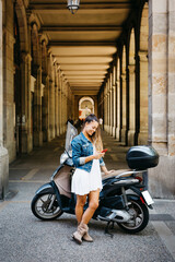 Fototapeta na wymiar Young smiling woman on a motorbike using a red smartphone