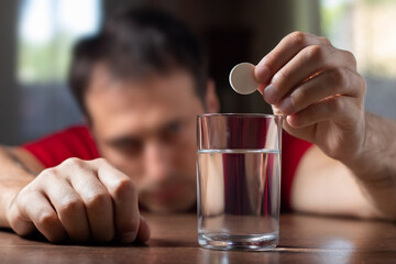 Man taking medicine for hangover at home, focus on hand with pill