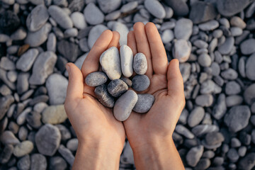 girls holding grey smooth pebbles at the beach. High quality photo