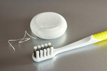 Dental floss and a toothbrush on a gray background. Dental care.