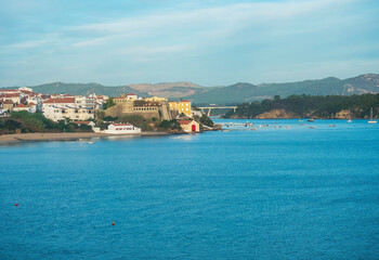 View over the sea on Vila Nova de Milfontes with Praia da Franquia sand beach, mouth of Mira river, Forte de Milfontes and green vegetation. Golden hour light