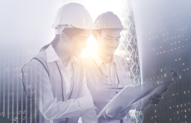 Engineer and architect smiling Discuss, review the construction drawings, blueprints, plan the construction work and renovate project on high rise building background