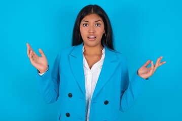 Surprised terrified Young latin woman wearing  blue blazer blue Gestures with uncertainty, stares...