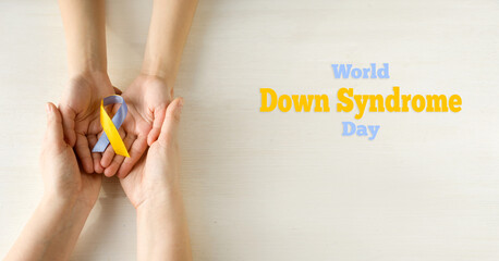 World Down syndrome day. Mom and baby are holding blue and yellow ribbon on white background. Down...