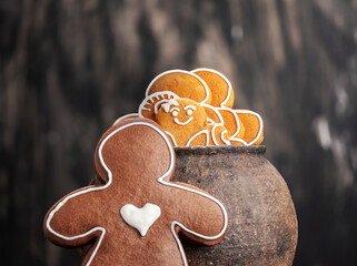 Collection of various gingerbread men in a pot on wooden background