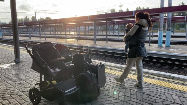 Family with little child traveling by train, woman with baby and luggage on Simferopol railway station platform waiting for arrival of the train.