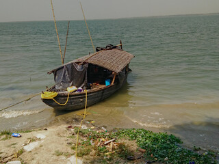 wooden asian boat tied to river ganga shore in west bengal india