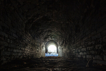 Historical underground red brick passage. Light at the end of tunnel
