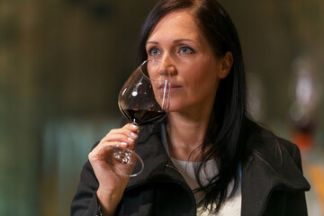 Woman tasting wine at the wine cellar with barrels in background