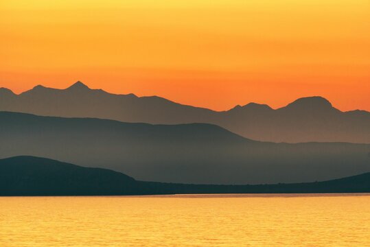 Illustration of a mountain range behind a seascape at sunset
