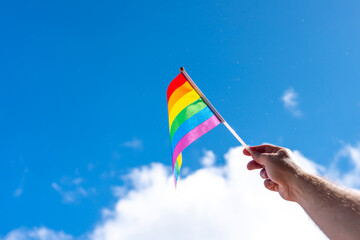 A small rainbow flag pointing to the sky as a sign of a sexual minority in a hand