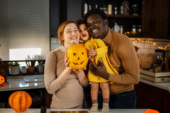 Multi-Ethnic family with the small child preparing for Halloween holiday having fun with jack -o -lantern