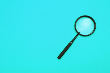 Loupe or magnifying glass on a turquoise background. Shallow depth of field