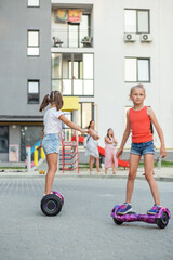 Happy children riding on hoverboards or gyro scooters outdoors in summer. Active life concept.