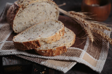 Sliced fresh baked whole grain bread with oats, flax seeds and sesame seeds on rustic wooden board. Bakery products