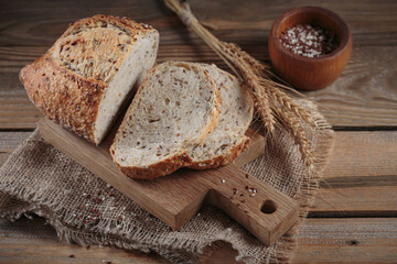 Sliced fresh baked whole grain bread with oats, flax seeds and sesame seeds on rustic wooden board. Bakery products