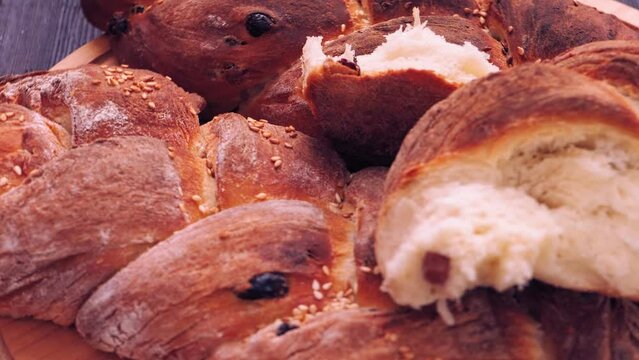 Shabbat challah bread with sesame seeds and raisins rotates in a circle on a wooden table. Close-up