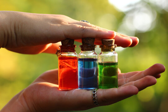 Magical elixirs of a potion in bottles holding in hands