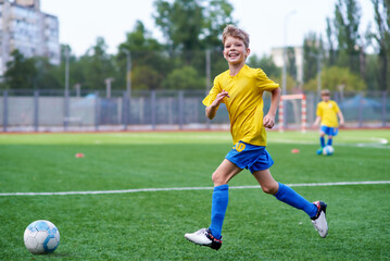 Football soccer training for kids. Smiling boy attending soccer training on school field. Soccer...