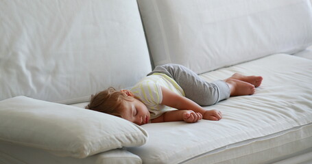 Candid baby sleeping on sofa in the afternoon nap. Cute infant toddler asleep