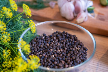 ingredients for homemade pickles - dill, garlic, pepper and spices, rustic wooden table, homemade pickles, canning for the winter, a bowl of black pepper