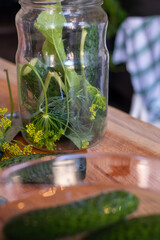 handmade marinated or pickled cucumbers with dill, garlic, and spices in a bowl and jar, rustic wooden table, homemade pickles, canning for the winter 