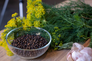 ingredients for homemade pickles - dill, garlic, pepper and spices, rustic wooden table, homemade pickles, canning for the winter, a bowl of black pepper