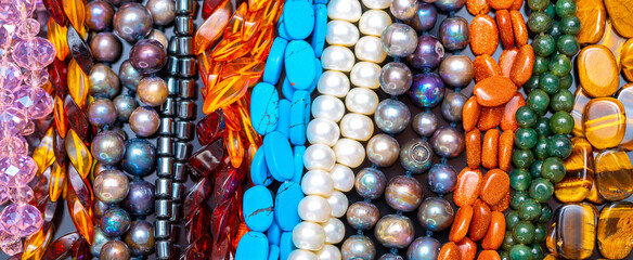 Beads and necklaces made of colored semi precious stones. Background from a variety of beautiful...