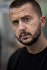 Fototapeta premium Bearded depressed person looks to a camera. Portrait of sad young adult caucasian man. 