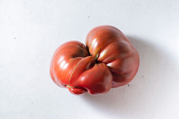 Ugly tomato on a light surface. Mutant.